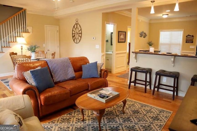 living area featuring stairs, light wood-type flooring, and ornamental molding