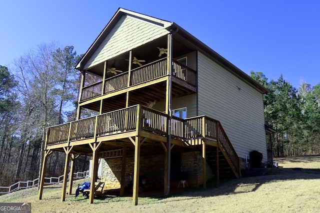 back of house featuring ceiling fan, stone siding, a deck, and stairway