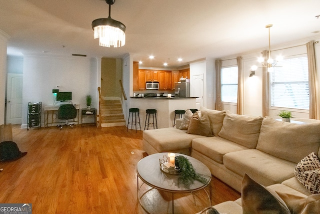 living room featuring an inviting chandelier, crown molding, and light hardwood / wood-style flooring