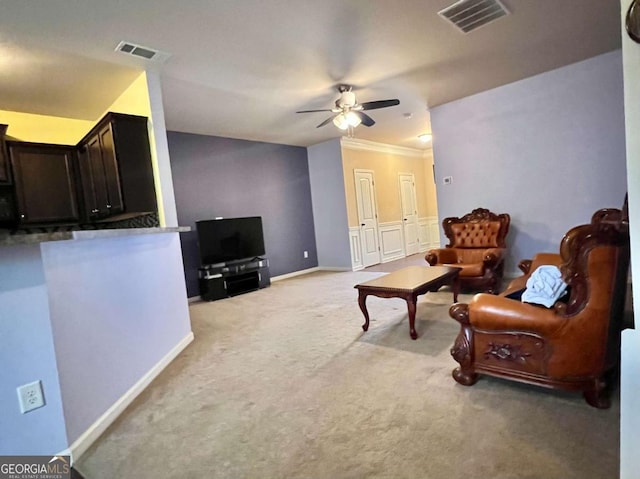 carpeted living room with crown molding and ceiling fan