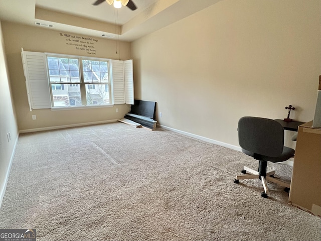 unfurnished office with ceiling fan, a raised ceiling, and carpet