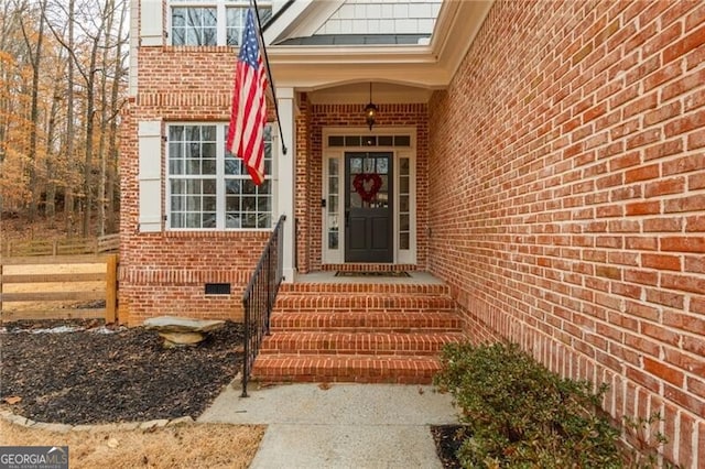 property entrance featuring brick siding and crawl space