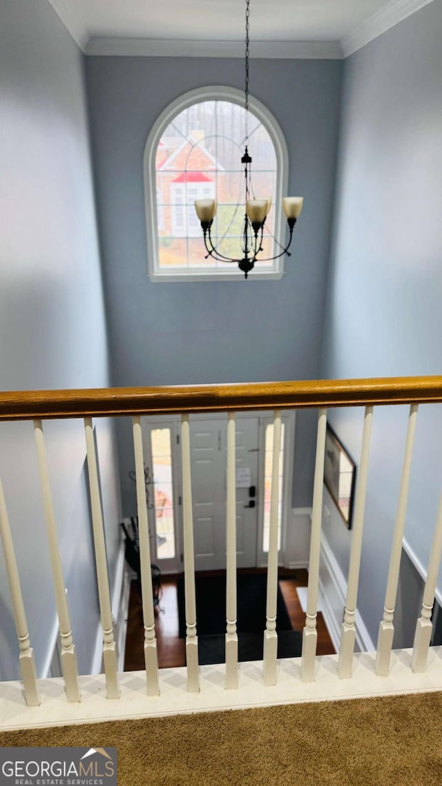 staircase with crown molding, carpet flooring, and an inviting chandelier