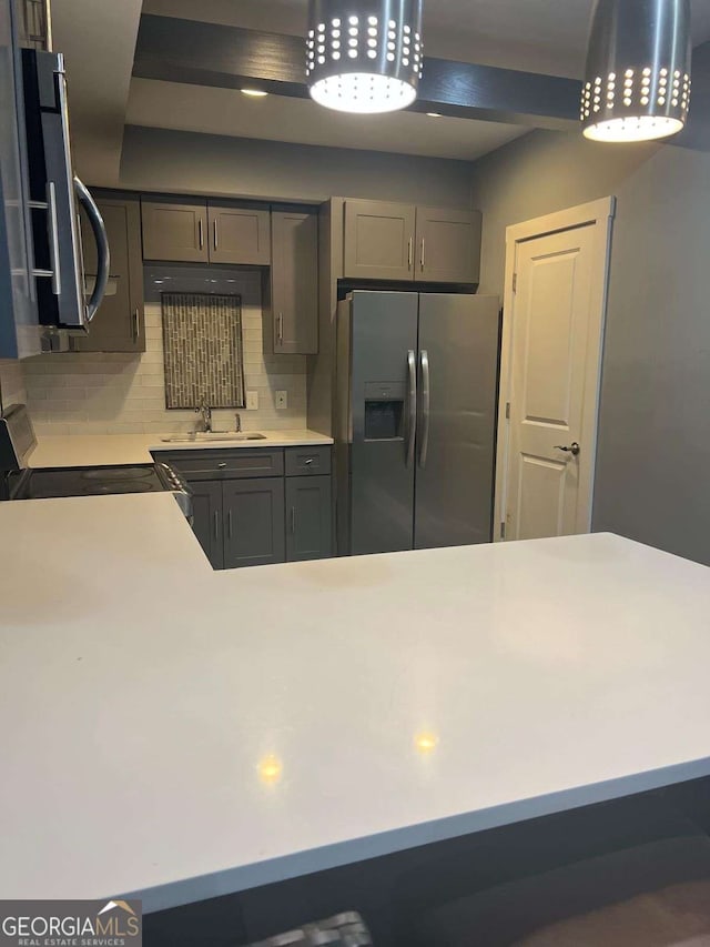 kitchen featuring gray cabinetry, sink, backsplash, and stainless steel appliances