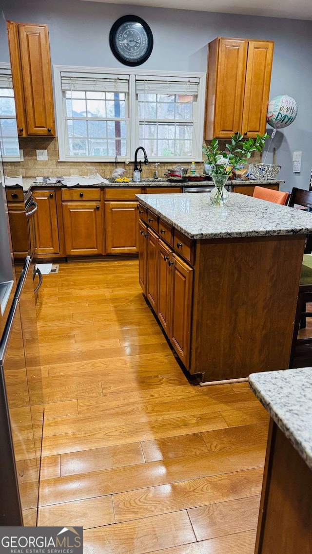 kitchen featuring sink, light stone countertops, light hardwood / wood-style floors, and a kitchen bar