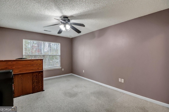 unfurnished office with light colored carpet, a textured ceiling, and ceiling fan