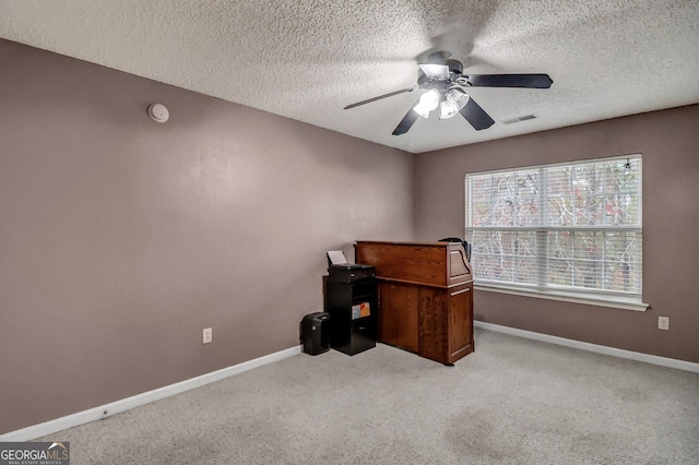 carpeted home office featuring a textured ceiling and ceiling fan