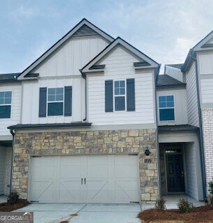 view of front of house featuring a garage, stone siding, driveway, and board and batten siding