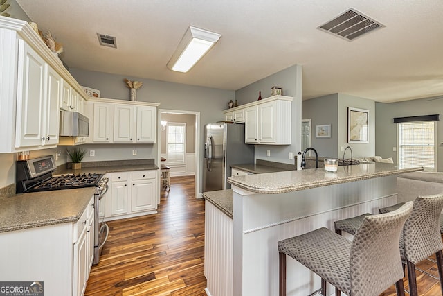 kitchen with stainless steel appliances, white cabinetry, a breakfast bar area, and kitchen peninsula