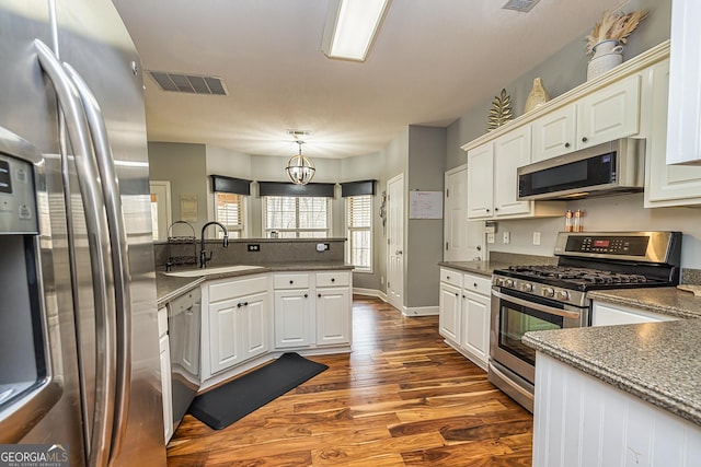 kitchen with pendant lighting, sink, stainless steel appliances, and white cabinets