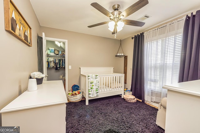 bedroom featuring a crib, a closet, ceiling fan, and carpet flooring