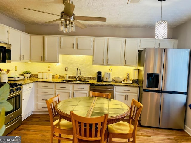 6594 Meadow Green Cir, Peachtree Corners, GA 30092 - kitchen with stainless steel appliances, a sink, a ceiling fan, dark stone countertops, and white cabinets