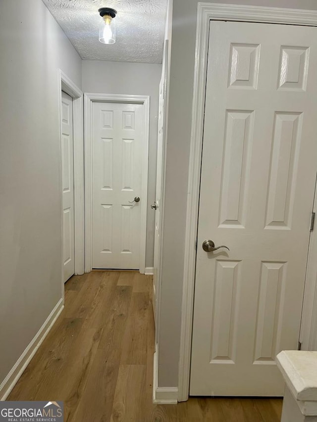 6594 Meadow Green Cir, Peachtree Corners, GA 30092 - hall featuring light wood-type flooring, a textured ceiling, and baseboards