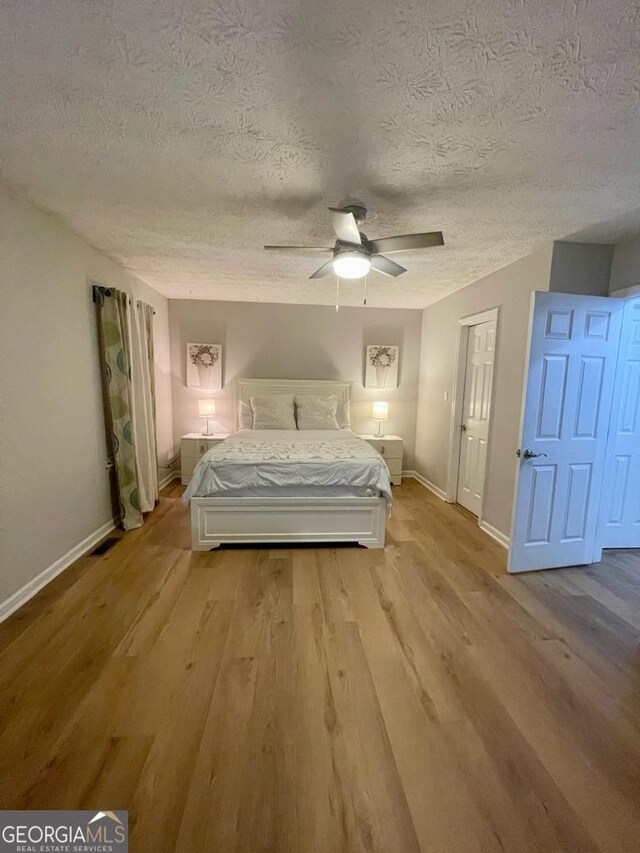 6594 Meadow Green Cir, Peachtree Corners, GA 30092 - bedroom with wood finished floors, a textured ceiling, baseboards, and ceiling fan