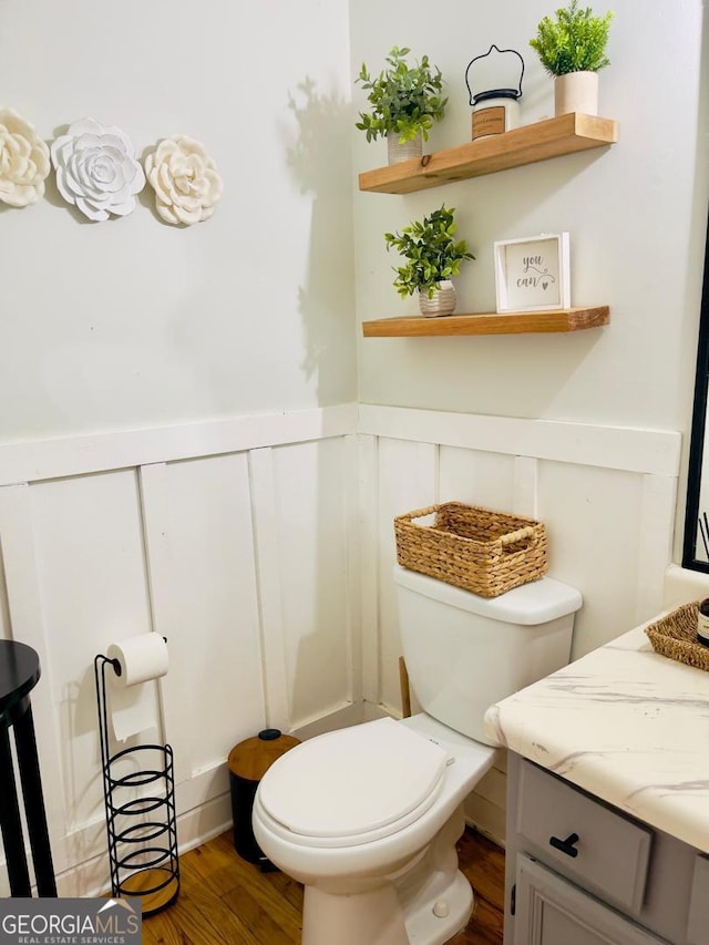 6594 Meadow Green Cir, Peachtree Corners, GA 30092 - bathroom with vanity, wood finished floors, a wainscoted wall, toilet, and a decorative wall