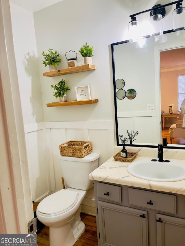 6594 Meadow Green Cir, Peachtree Corners, GA 30092 - bathroom featuring vanity, wood finished floors, toilet, a wainscoted wall, and a decorative wall