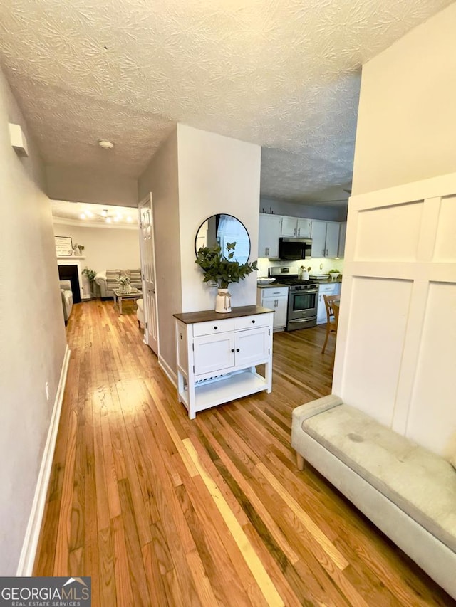6594 Meadow Green Cir, Peachtree Corners, GA 30092 - hallway with light wood-style flooring, a textured ceiling, and baseboards