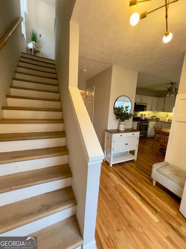 6594 Meadow Green Cir, Peachtree Corners, GA 30092 - stairs featuring wood finished floors and a textured ceiling