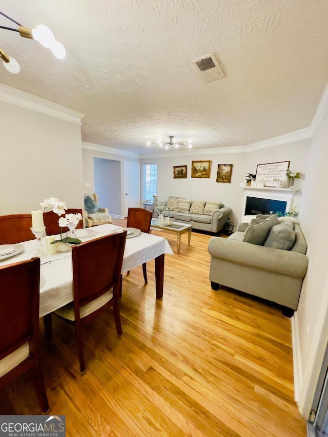 6594 Meadow Green Cir, Peachtree Corners, GA 30092 - living room featuring light wood-style flooring, crown molding, a textured ceiling, and a chandelier