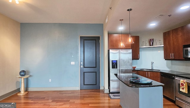 kitchen featuring sink, light hardwood / wood-style flooring, appliances with stainless steel finishes, a kitchen island, and decorative light fixtures