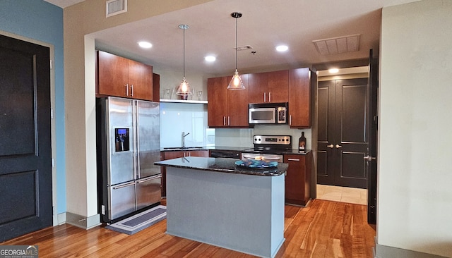 kitchen featuring sink, appliances with stainless steel finishes, a center island, light hardwood / wood-style floors, and decorative light fixtures