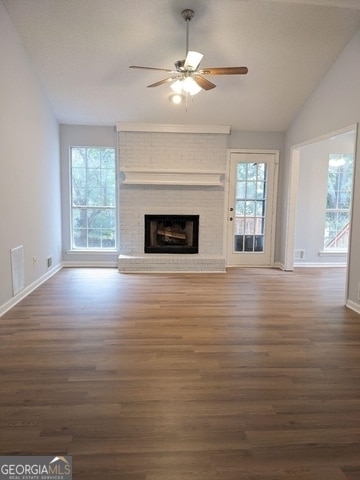 unfurnished living room with ceiling fan, lofted ceiling, dark hardwood / wood-style flooring, and a brick fireplace