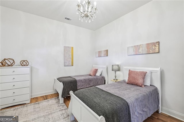 bedroom with hardwood / wood-style flooring and an inviting chandelier