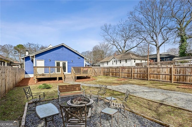 rear view of property featuring a lawn, a deck, and an outdoor fire pit