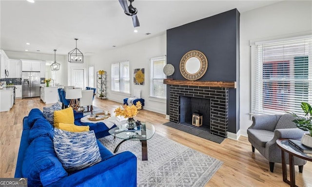 living room featuring a brick fireplace and light wood-type flooring