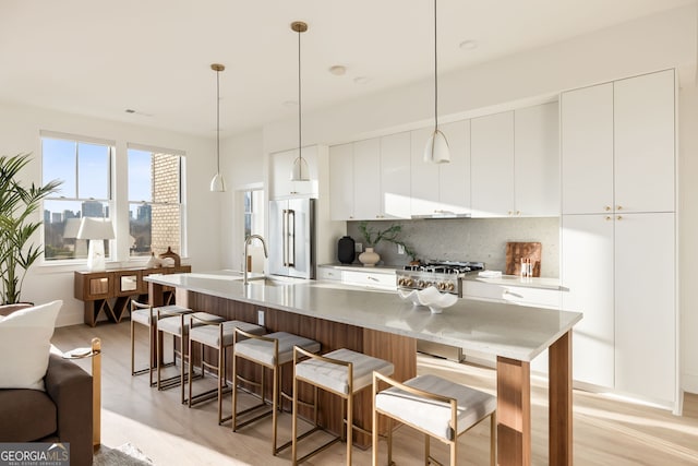 kitchen with tasteful backsplash, light countertops, white cabinetry, high quality fridge, and modern cabinets