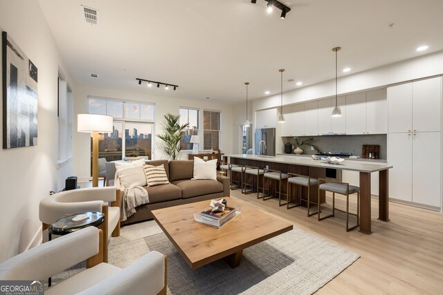 living room featuring light wood-type flooring, visible vents, track lighting, and recessed lighting