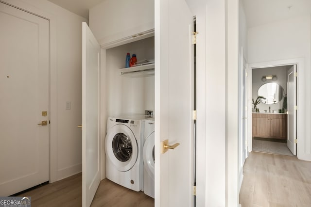 clothes washing area with laundry area, independent washer and dryer, and light wood-style flooring