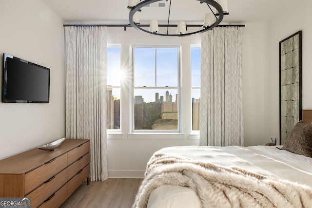 bedroom with an inviting chandelier, baseboards, and wood finished floors