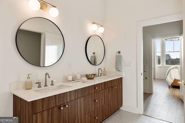 ensuite bathroom with connected bathroom, a sink, baseboards, and double vanity