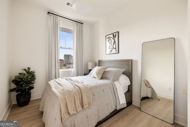 bedroom with light wood-style flooring, visible vents, and baseboards