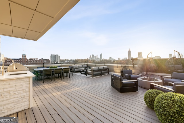 wooden deck with area for grilling, an outdoor living space with a fire pit, and a city view