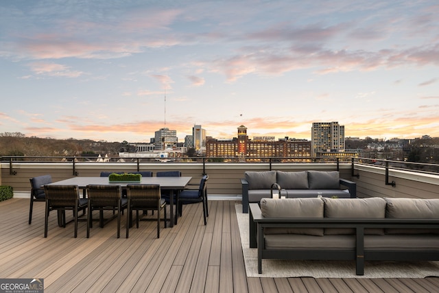 deck at dusk featuring outdoor dining area, an outdoor hangout area, and a city view