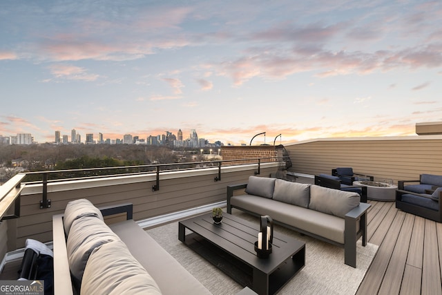 deck at dusk featuring a city view and an outdoor living space with a fire pit