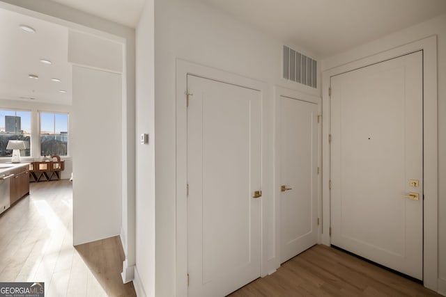 hall featuring light wood finished floors and visible vents