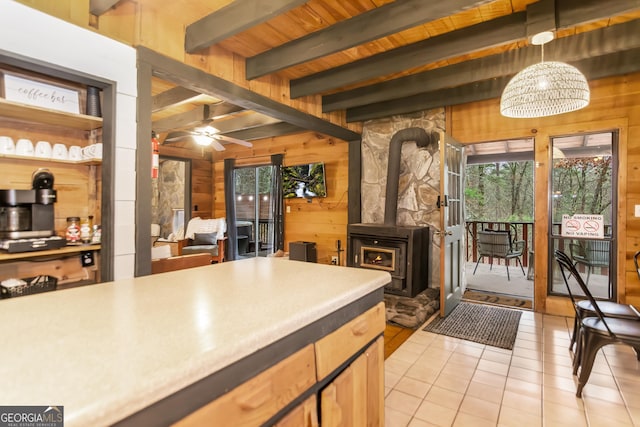 kitchen with a wood stove, wooden walls, a healthy amount of sunlight, and decorative light fixtures