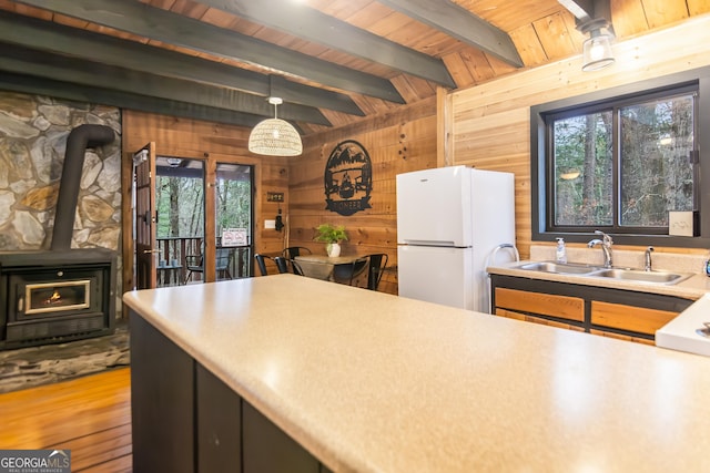 kitchen featuring wood ceiling, wood walls, white refrigerator, sink, and pendant lighting