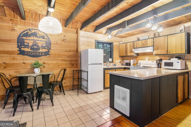 kitchen with white appliances, wood walls, and pendant lighting