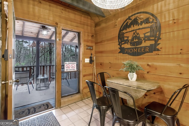 tiled dining space featuring wooden ceiling and wooden walls