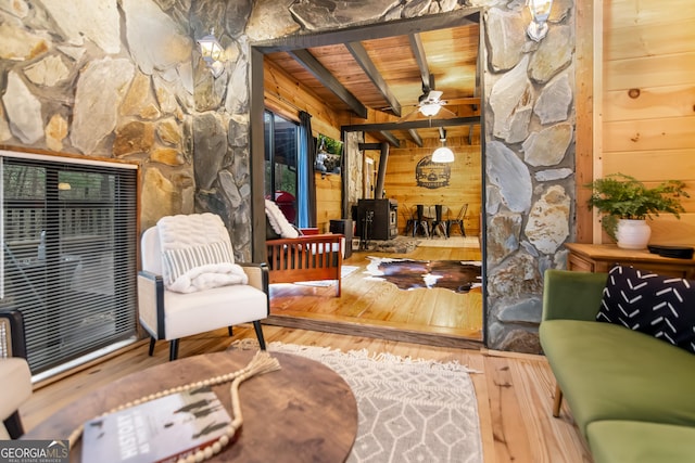 living area with hardwood / wood-style flooring, beamed ceiling, wood walls, and wood ceiling