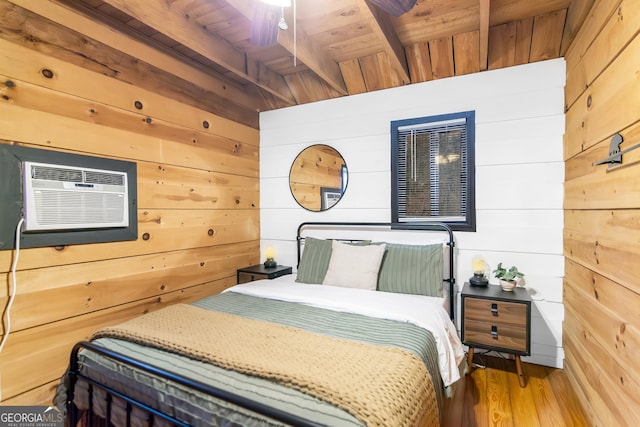 bedroom featuring beam ceiling, wood-type flooring, wood walls, wooden ceiling, and a wall unit AC