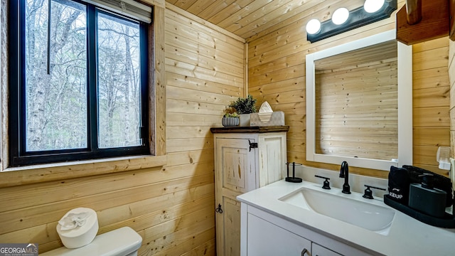 bathroom featuring toilet, wooden walls, wooden ceiling, and vanity