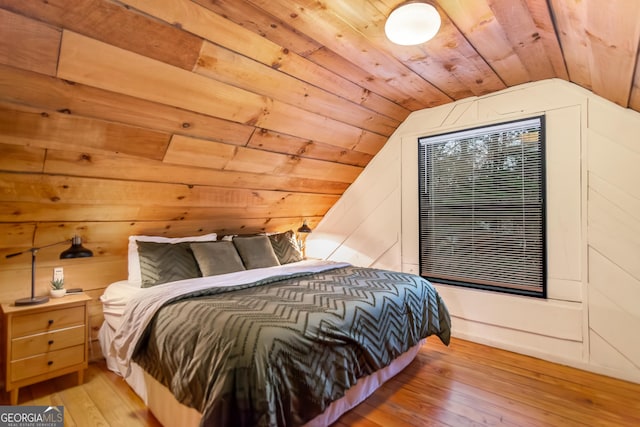 bedroom with light hardwood / wood-style flooring, wooden walls, wooden ceiling, and lofted ceiling