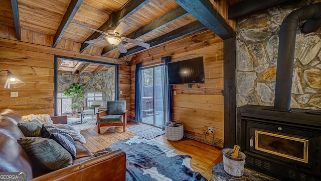 living room with a wood stove, hardwood / wood-style floors, wooden walls, and wood ceiling