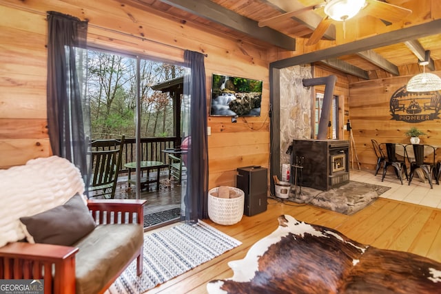 interior space with hardwood / wood-style floors, beamed ceiling, wood walls, a wood stove, and wooden ceiling