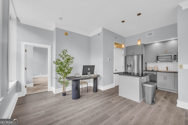 kitchen with gray cabinets, hanging light fixtures, stainless steel appliances, a kitchen island, and light wood-type flooring